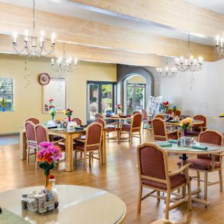 A spacious and inviting dining area featuring elegant chandeliers and vibrant floral arrangements.