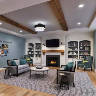 A modern living room featuring a fireplace flanked by bookshelves, comfortable seating, and decorative wood ceiling beams.