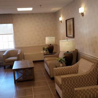 A cozy seating area with chairs, a sofa, and a table complemented by warm lighting.