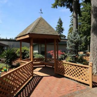 A charming gazebo nestled in a beautifully landscaped garden, inviting relaxation on a sunny day.
