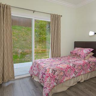 A cozy bedroom featuring floral bedding and sliding doors that open to a serene outdoor view.