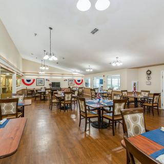 A spacious dining room with neatly arranged tables and chairs, decorated with patriotic-themed banners.