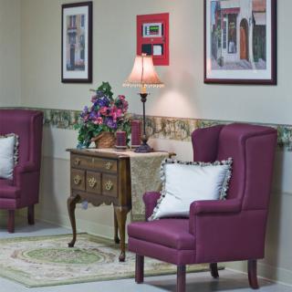 A cozy sitting area with purple armchairs, a small table, and decorative artwork on the walls.