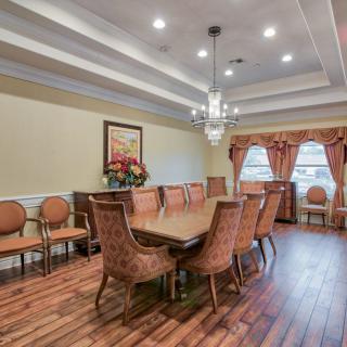 A well-decorated dining room with a large table and elegant chairs, featuring a chandelier and wooden flooring.