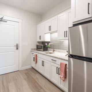 A modern kitchen with white cabinets and stainless steel appliances.