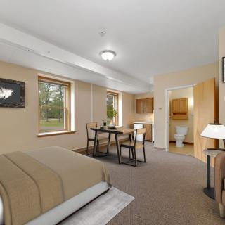 A spacious bedroom with a cozy dining area, featuring modern furniture and neutral tones.