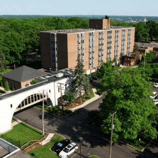 An aerial view of a building surrounded by trees and cars on the road.
