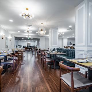A modern restaurant interior with neatly arranged tables and chairs on a wooden floor.