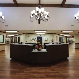 A spacious lobby area featuring a central reception desk and elegant chandeliers.