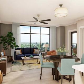 A modern living room with a cozy dining area, featuring large windows and natural lighting.
