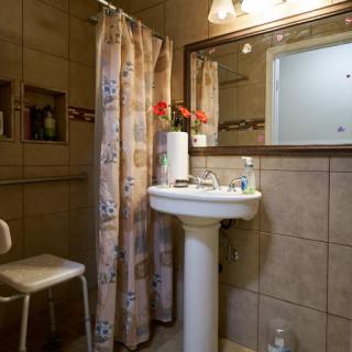 A cozy bathroom with a pedestal sink, mirror, and floral shower curtain.