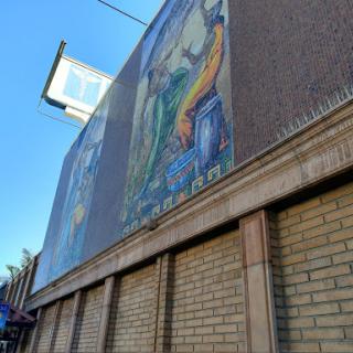 A vibrant mural adorns the side of a building, showcasing colorful artwork against a clear blue sky.