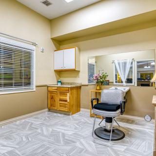 A modern hair salon with a single styling chair, mirror, and cabinetry.
