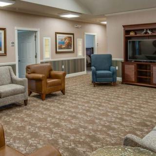 A spacious living room with various seating options and a large television.