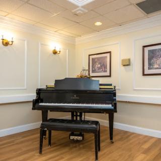 A beautifully arranged space featuring a black grand piano, complemented by elegant wall art and soft lighting.