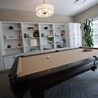 A stylish game room with a pool table and built-in shelves filled with decorations.