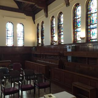 An interior view of a church with stained glass windows and wooden seating.