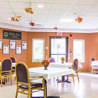 A brightly lit dining area with tables and chairs, adorned with autumn-themed decorations.