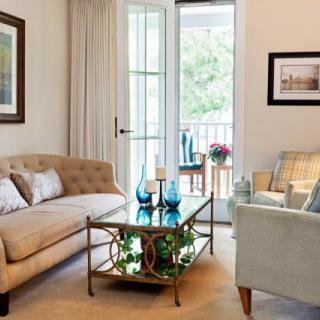 A cozy living room featuring a beige sofa, armchair, and decorative coffee table with natural light streaming in through the window.