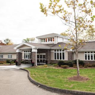 A modern building with a landscaped entrance and a driveway.