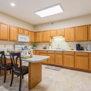 A modern kitchen with wooden cabinets, a small dining table, and various appliances.