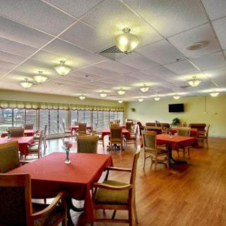 A spacious dining room with red tablecloths and ample lighting.