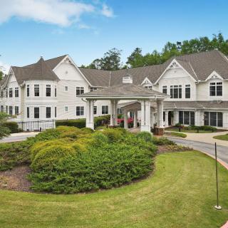 A large, elegant residential building surrounded by well-maintained gardens.