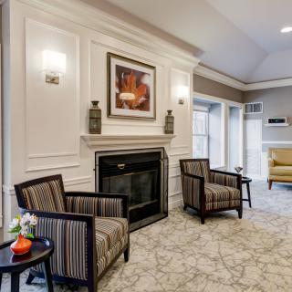 A cozy lobby area featuring a fireplace, elegant chairs, and modern decor.