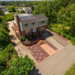 Aerial view of a house with a patterned driveway surrounded by trees in a residential area.