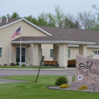 A church building with an American flag flying outside and a stone sign displaying its name.