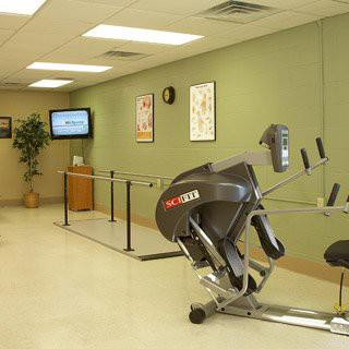 A physical therapy room with exercise equipment and walking bars.