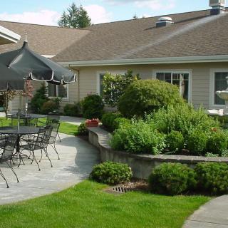 A well-maintained patio area with outdoor seating, surrounded by lush greenery and landscaping.