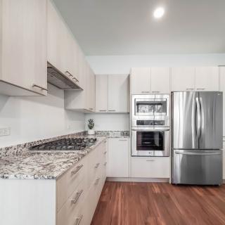 A modern kitchen with stainless steel appliances, granite countertops, and wood flooring.