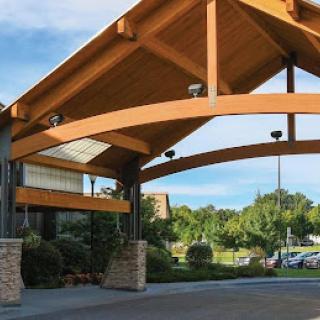 A modern architectural entrance featuring a wooden canopy and landscaped surroundings.