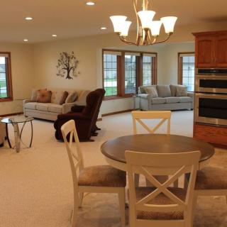 An open-concept living and dining area featuring comfortable seating, a round dining table, and large windows.