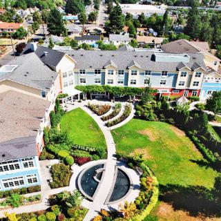Aerial view of a landscaped garden with a central fountain and surrounding buildings.