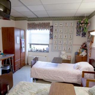 A shared room in a nursing home with two beds and furniture.