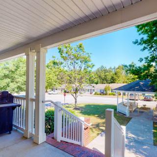 A peaceful view from the porch, showcasing a sunny day and a vibrant garden.