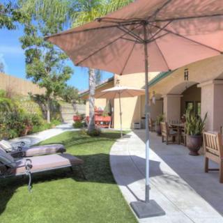 A sunny backyard with patio furniture and umbrellas, perfect for relaxing.