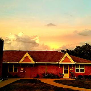 A charming house framed by a beautiful sunset sky.