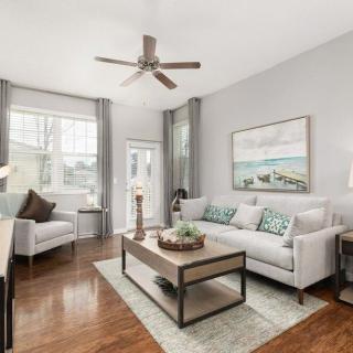 A modern living room with neutral colors, featuring a cozy sofa, a coffee table, and decorative wall art.