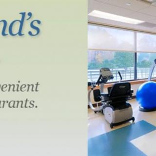 A fitness center with exercise equipment and a large window providing natural light.