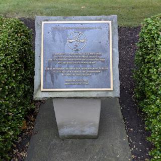 A memorial plaque set in a landscaped area, commemorating an important event or individual.