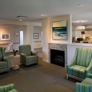 A cozy living room with green armchairs and a fireplace, featuring modern artwork on the walls.