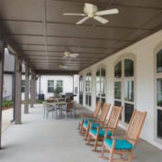 A covered porch with rocking chairs and a ceiling fan, offering a cozy outdoor seating area.