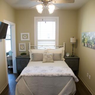 A cozy bedroom with a neatly made bed, wall-mounted TV, and elegant decor.