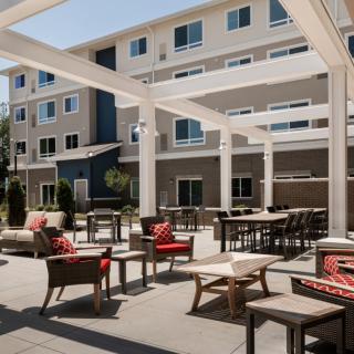A modern apartment complex with an outdoor patio featuring comfortable seating and tables.