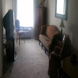 A cozy living room with a sofa, armchair, television, and a large window.