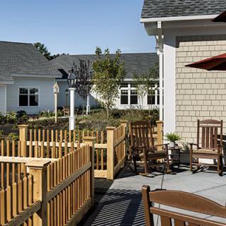 An outdoor seating area with wooden chairs, a fence, and an umbrella in a residential setting.