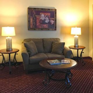 A cozy living room setup with a sofa, coffee table, and lamps under warm lighting.